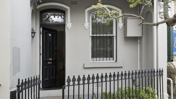 A building facade with a black door, a window with metal bars, and a decorative metal fence. - Entire 2 Bedroom Paddington Terrace (Paddington)