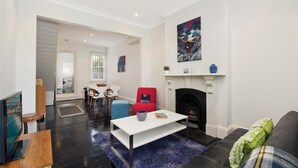 A modern living room with a fireplace, a red armchair, a blue sofa, and a white coffee table. - Entire 2 Bedroom Paddington Terrace (Paddington)