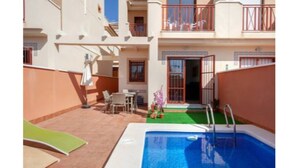 A pool area with a diving board, a small table with chairs, and a door leading to a covered entrance. - Flagship Private Villa 3bed + pool - sleeps 6 Mazarron (FREE WIFI & Air-con)! (Mazarrón)