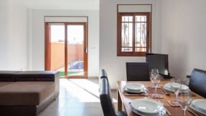 A dining area with a table set for four, a television, and a sliding glass door leading to an outdoor area. - Flagship Private Villa 3bed + pool - sleeps 6 Mazarron (FREE WIFI & Air-con)! (Mazarrón)
