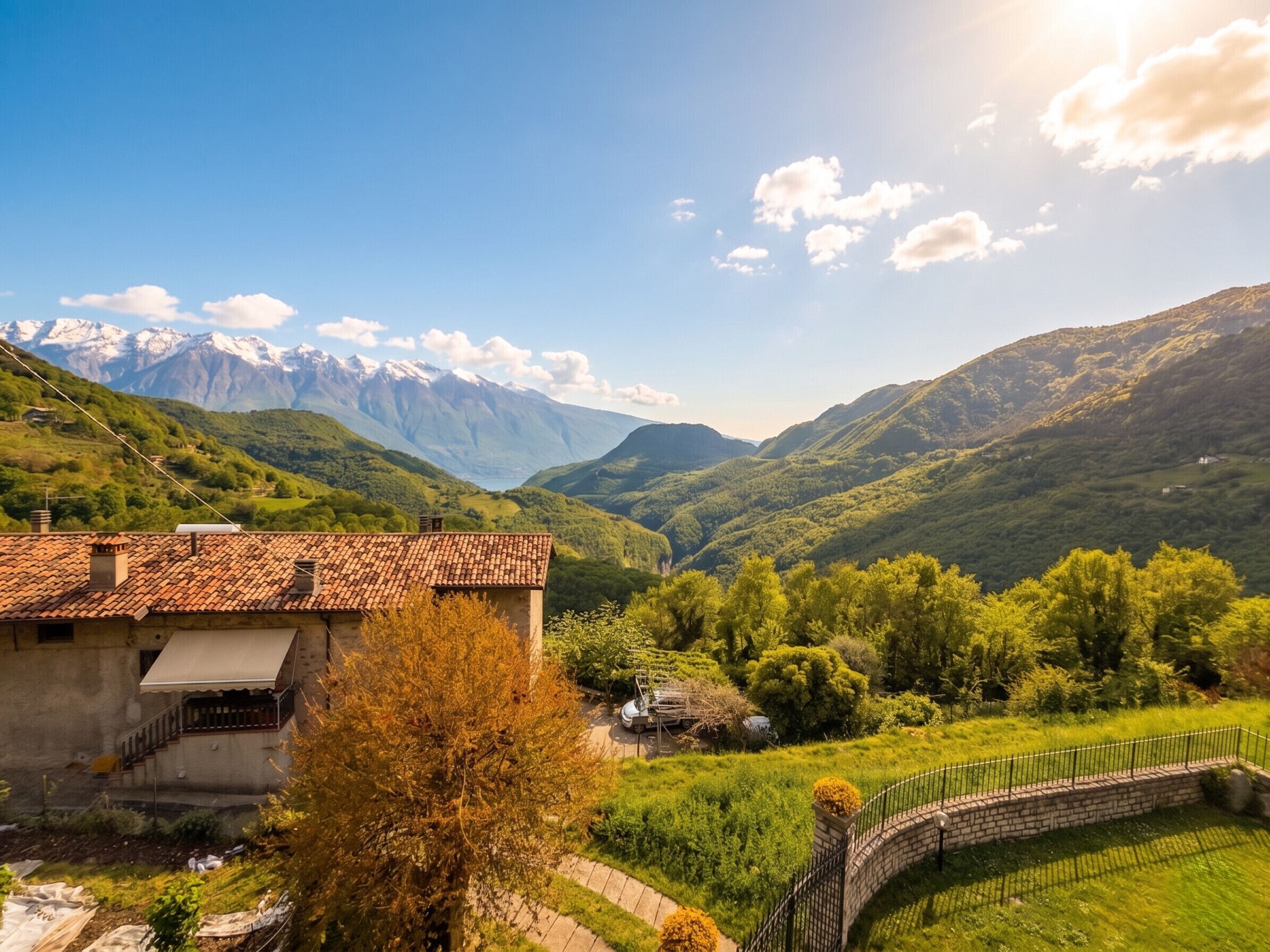Una casa rural amb teulada de teules, envoltada de vegetació abundant i muntanyes al fons.