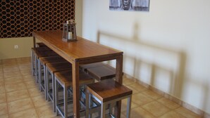 Een eetgedeelte met een lange houten tafel en banken, een honingraatwand en een Boeddha-schilderij.
