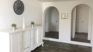 A hallway with a white cabinet, a clock, and two arched doorways.