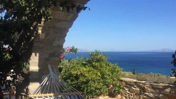 A hammock under a stone archway overlooking a coastal view.