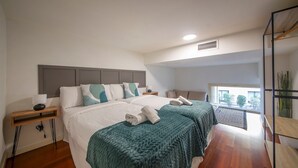 A modern bedroom with a large bed, a bedside table with a lamp, and a view of the outdoors through a window. - Four bedroom apartment Ronda Sant Pere - You Stylish (Barcelona)