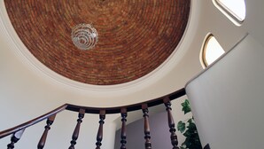 Un escalier en colimaçon avec un plafond en briques et un luminaire suspendu.