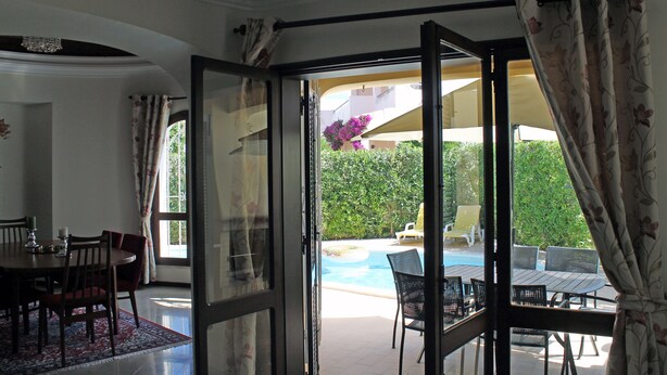 Une porte-fenêtre coulissante donne accès à un espace piscine aménagé avec du mobilier d’extérieur.