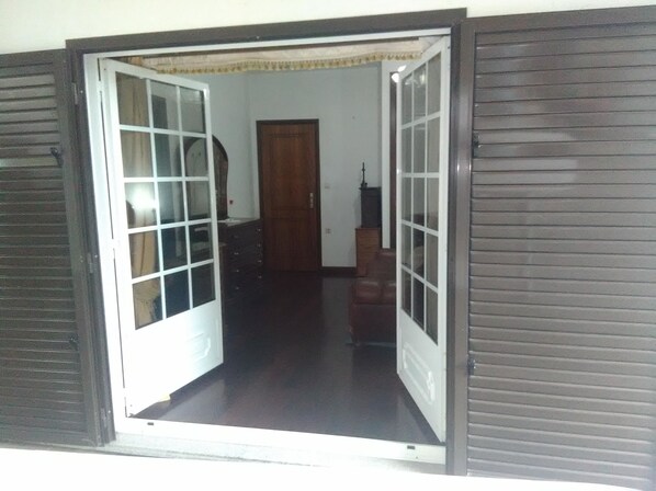 A room with a wooden door, a small cabinet, and a lamp.