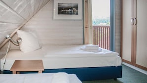 Un lit simple avec une tête de lit bleue, une petite table en bois et un tableau encadré accroché au mur.