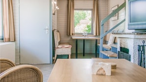 Une cuisine compacte comprenant une table à manger, des chaises en osier, un petit îlot central et un téléviseur fixé au mur.