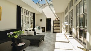 En rummelig stue med højt til loftet, ovenlysvindue, sofa, sofabord og spiseområde med bord og stole.