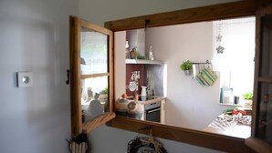 A kitchen with a wooden-framed window, a refrigerator, and various kitchen items.