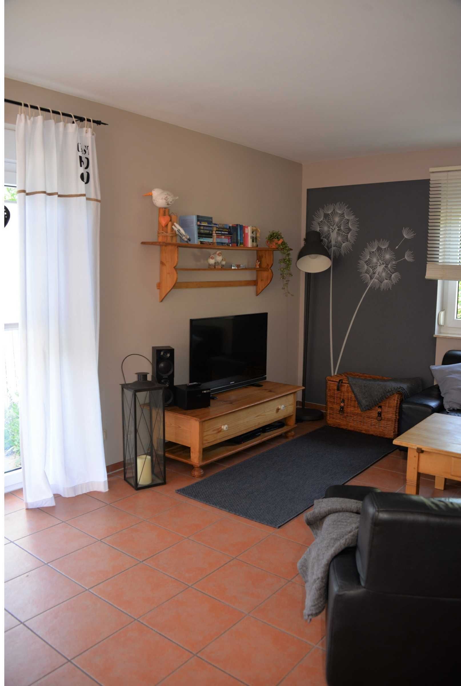 A living room with a TV, bookshelf, and a dandelion wall decoration.