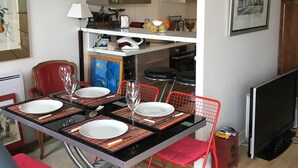 A dining area with a table set for four, red chairs, and a television in the corner.