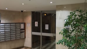 A lobby with a glass door entrance, a plant, and a row of filing cabinets.