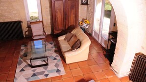 Un salon avec une table basse en verre, un canapé beige, un meuble en bois et un radiateur.