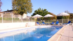 Une piscine aux carreaux bleus, entourée d’une clôture blanche et de chaises longues bleues.