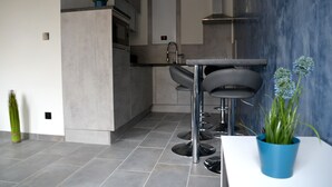 Una cocina moderna con baldosas grises, una encimera blanca y dos taburetes de bar.