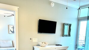 Un dormitorio con cama, cómoda, televisor y puerta que da a otra habitación.