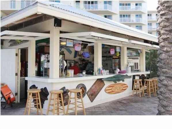 Un bar frente al mar con taburetes de madera y una barra.