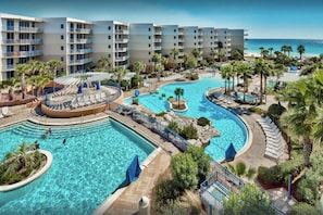 Un resort con varias piscinas, palmeras y vistas a la playa.