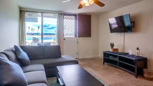 Una sala de estar con sofá, mesa de centro, televisor en la pared y ventilador de techo.