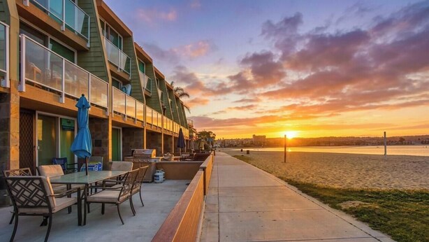 Un hotel frente a la playa con asientos al aire libre y vista al atardecer.