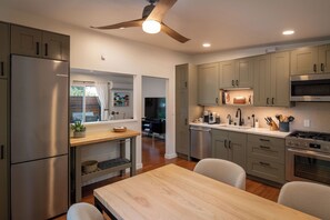 Eine moderne Küche mit Edelstahlgeräten, Holz Arbeitsplatten und einem Deckenventilator.