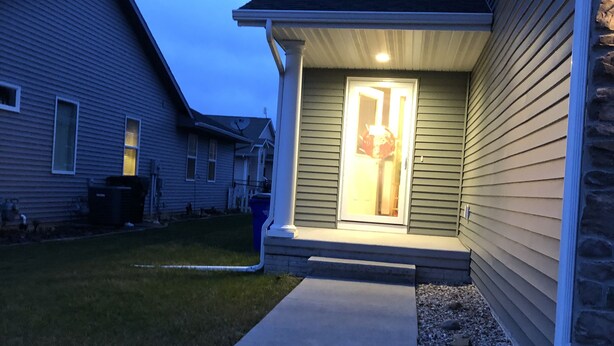 A residential house with a front porch, a visible door, and a pathway leading to the entrance.
