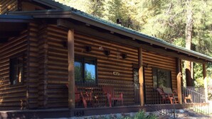 Eine Blockhütte mit Veranda, Nummer 1458, mit Sitzgelegenheiten im Freien und einem Kiesweg.