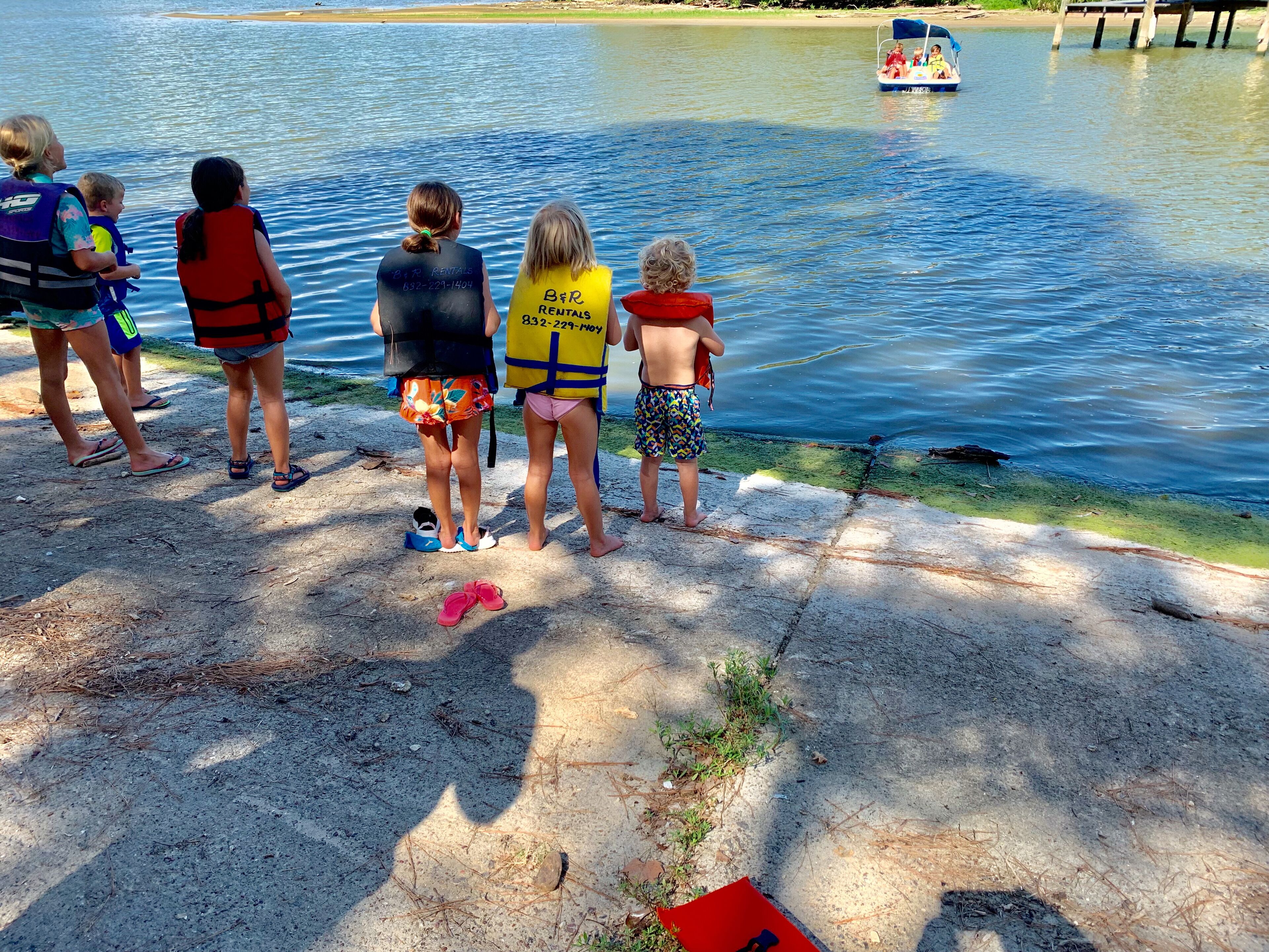 Een groep mensen staat bij een waterlichaam, sommigen dragen reddingsvesten.