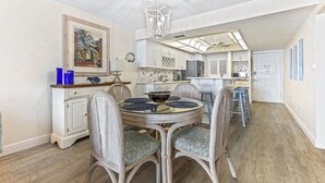 A dining area with a round table, wicker chairs, and a chandelier.