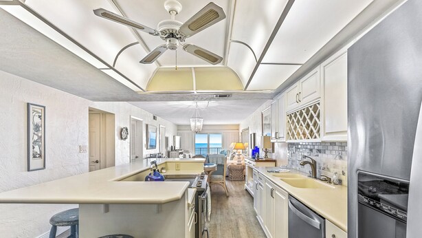 A modern kitchen with a central island, a ceiling fan, and a view to the outside.