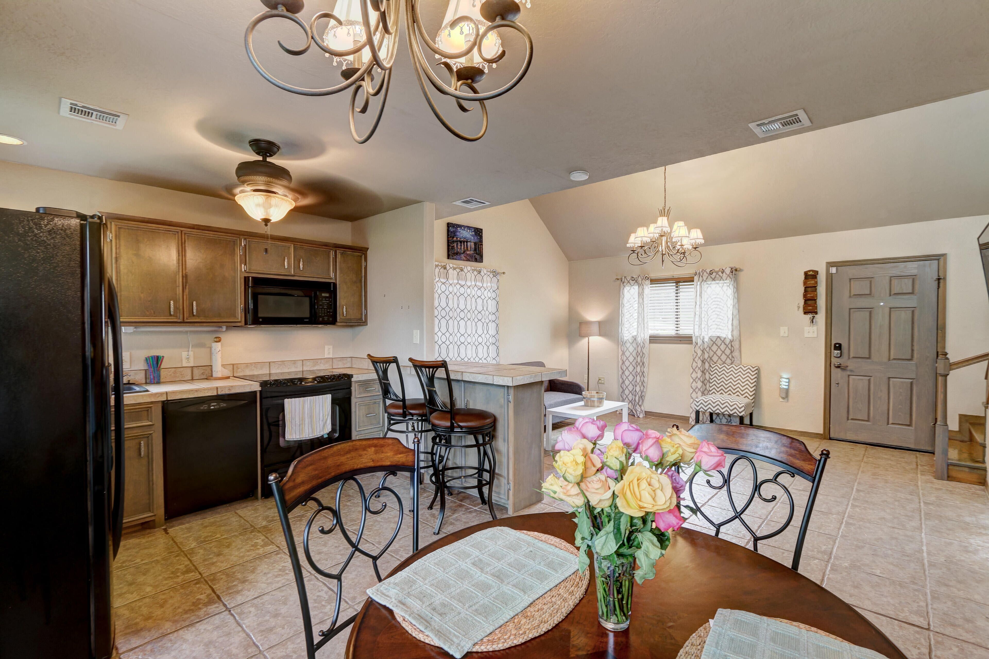A spacious kitchen with modern appliances, a dining area with a vase of flowers, and a staircase leading to another level.