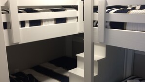 A bunk bed room with white railings and striped bedding. - Beautiful Cottage on Arbutus Lake, Traverse City, MI 49696 (Traverse City)
