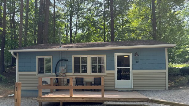 A small building with a gravel deck, a bench, and a door marked with the number 12. - Beautiful Cottage on Arbutus Lake, Traverse City, MI 49696 (Traverse City)