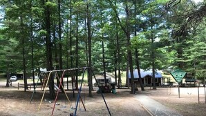 A campground with a swing set, picnic tables, and a covered picnic area. - Beautiful Cottage on Arbutus Lake, Traverse City, MI 49696 (Traverse City)