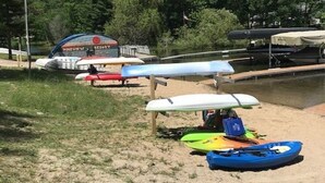 A sandy beach area with several kayaks and a covered structure labeled "Yaleview Resort." - Beautiful Cottage on Arbutus Lake, Traverse City, MI 49696 (Traverse City)