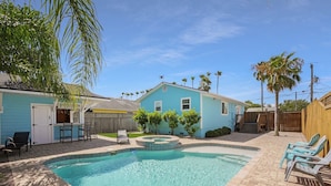 A backyard with a swimming pool, a blue house, and a wooden fence. - Sapphire: Updated 2 bedroom home with private pool, hot tub, cabana, outdoor (St. Augustine Beach)