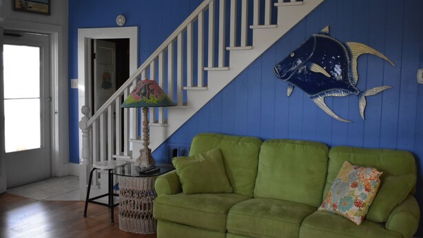 A room with a green sofa, a staircase with a blue wall, and a decorative fish mural. - Come, relax and enjoy all that Atlantic Beach has to offer!!  (Atlantic Beach)