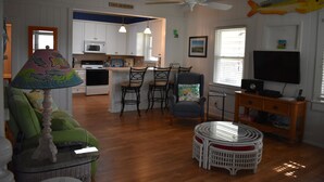 A living room with a green sofa, a glass coffee table, a white wicker table, and a television on a wooden stand. - Come, relax and enjoy all that Atlantic Beach has to offer!!  (Atlantic Beach)