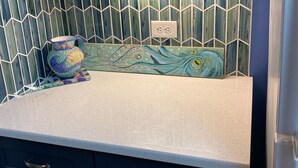 A kitchen with a white countertop, blue cabinets, and a mosaic backsplash. - Come, relax and enjoy all that Atlantic Beach has to offer!!  (Atlantic Beach)