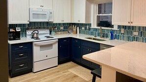A kitchen with white cabinets, a microwave, a stove, and a sink. - Come, relax and enjoy all that Atlantic Beach has to offer!!  (Atlantic Beach)