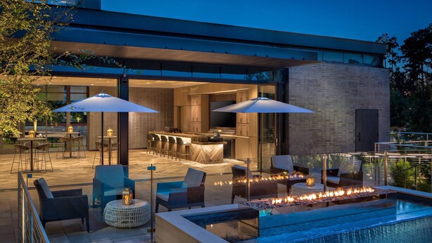 A modern outdoor pool area with seating and a bar. - Houston Cityplace Marriott at Springwoods Village (Spring)