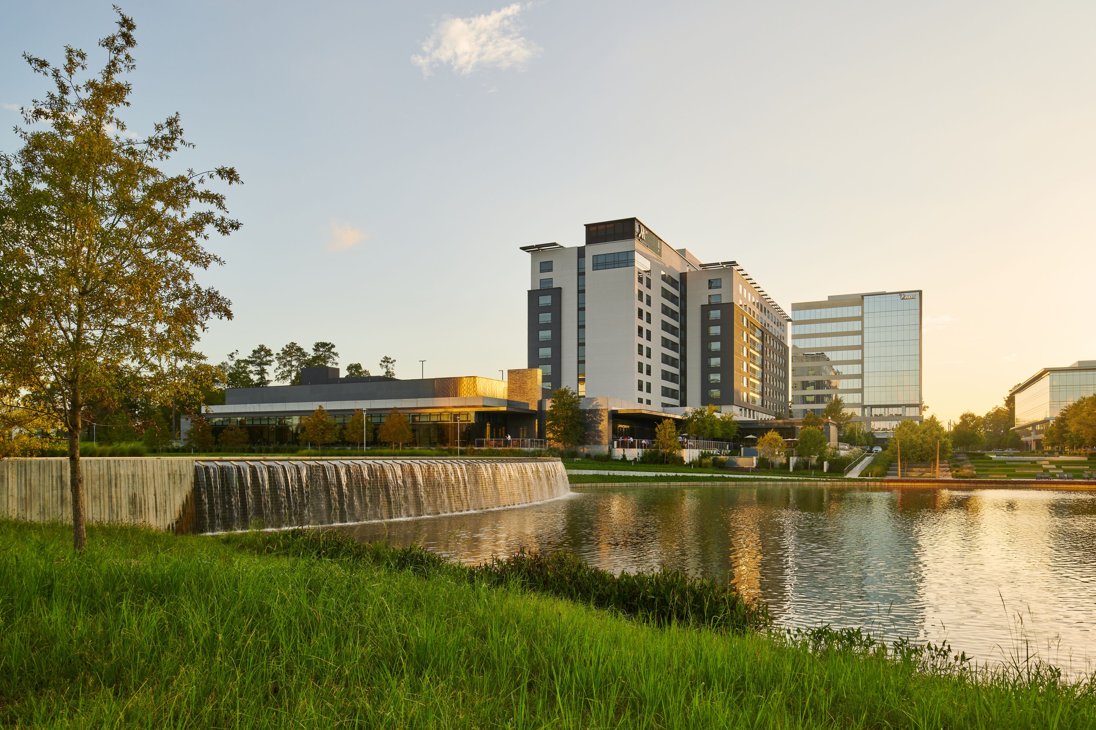 A modern building complex with a water feature in the foreground.