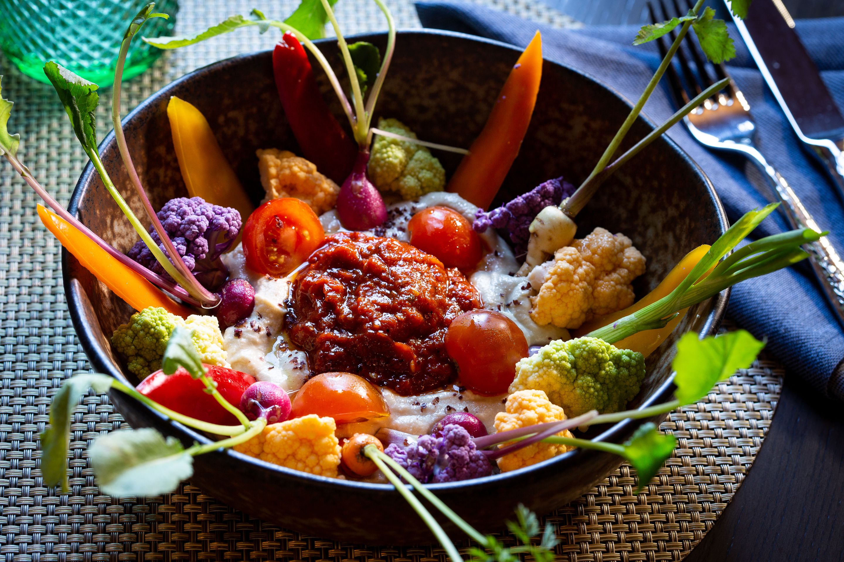 A bowl of colorful vegetables and a sauce centerpiece.
