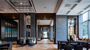 A spacious lobby with a herringbone wood floor, modern furniture, and large windows providing natural light. - Houston Cityplace Marriott at Springwoods Village (Spring)