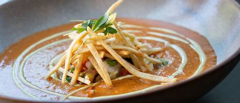 A bowl of soup with a creamy base and garnished with thin strips and green leaves.