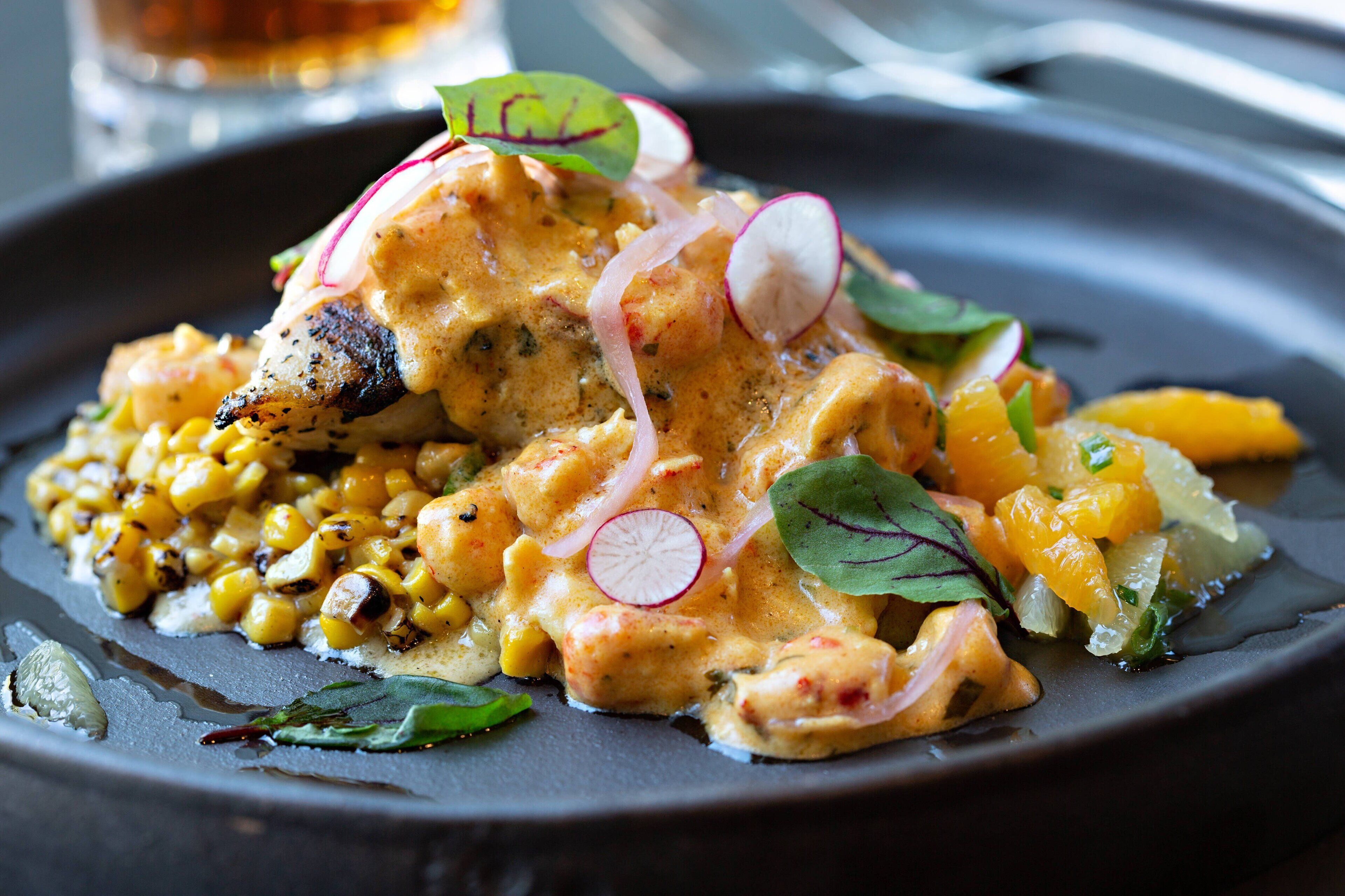 A plate of food with grilled chicken, corn, and vegetables.