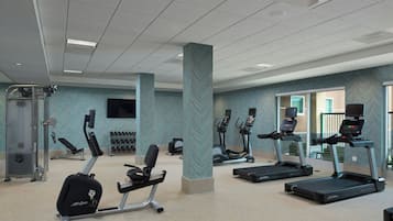 Un gimnasio con cintas de correr, elípticas y máquinas de pesas.